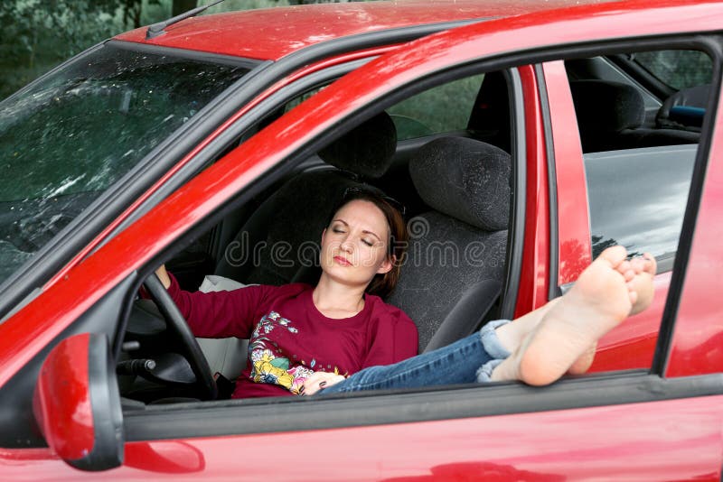 Der Fahrer der jungen Frau, der in einem roten Auto stillsteht, setzte ihre Füße auf das Autofenster, glückliches Reisekonzept stockbild Der Fahrer der jungen Frau, der in einem roten Auto stillsteht, setzte ihre Füße auf das Autofenster, glückliches Reisekonzept stockbild