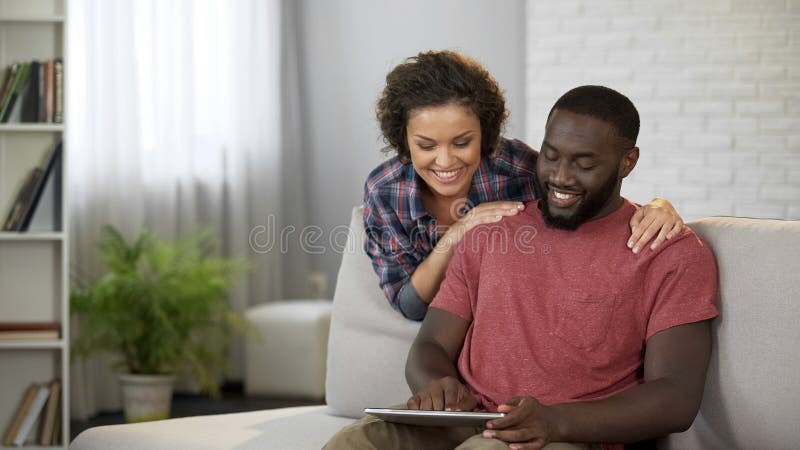 Happy men consulting with wife about buying new car, showing offers on tablet, stock photo. Happy men consulting with wife about buying new car, showing offers on tablet, stock photo