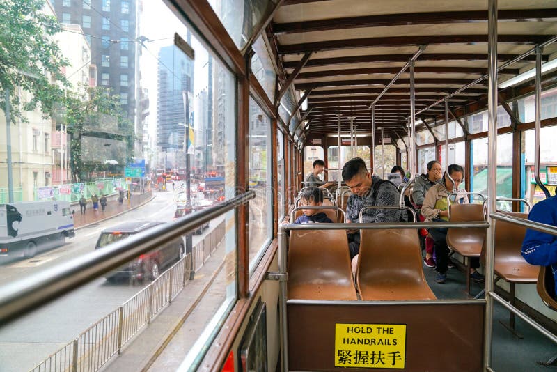 Der Innenraum einer Tram in Hong Kong mit Pendlern und der Ansicht des älteren Stadtteiles lizenzfreie stockbilder Der Innenraum einer Tram in Hong Kong mit Pendlern und der Ansicht des älteren Stadtteiles lizenzfreie stockbilder