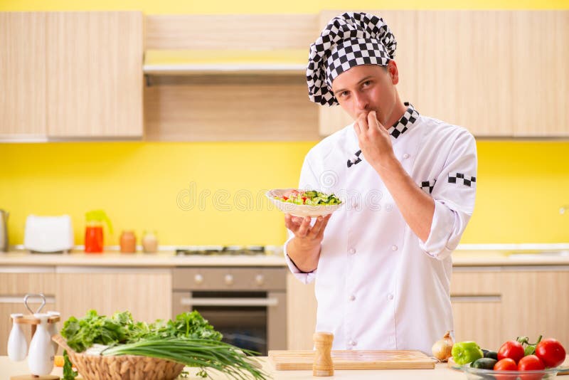 Der junge Berufskoch, der Salat an der Küche zubereitet stockbild Der junge Berufskoch, der Salat an der Küche zubereitet stockbild