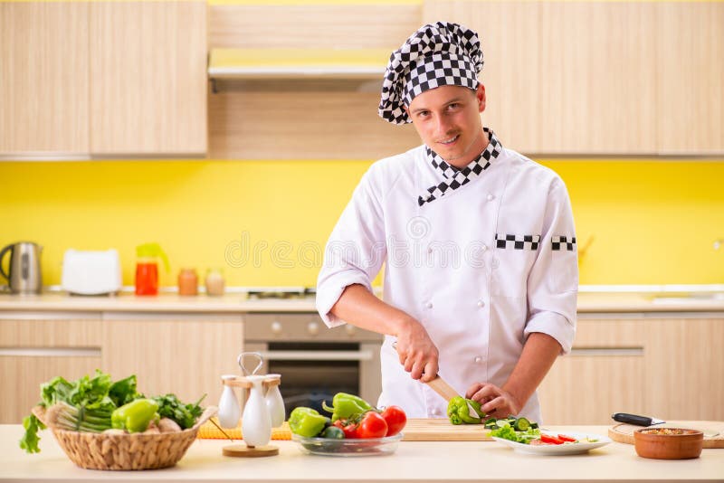 Der junge Berufskoch, der Salat an der Küche zubereitet stockfotografie Der junge Berufskoch, der Salat an der Küche zubereitet stockfotografie