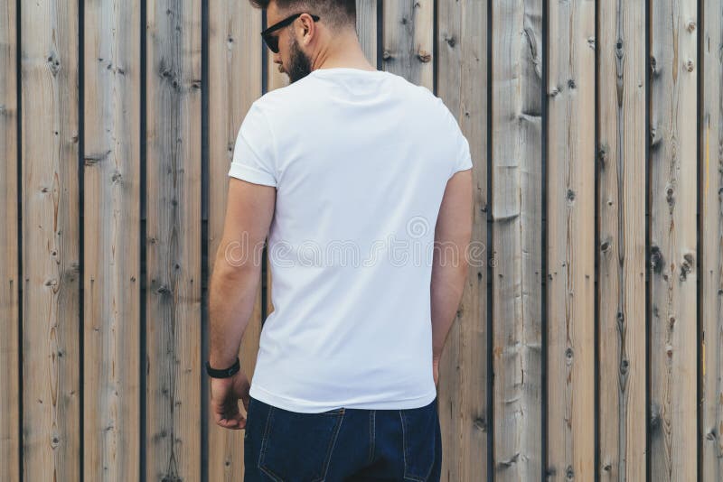 Der junge bärtige Hippie-Mann, der im weißen T-Shirt und in der Sonnenbrille gekleidet wird, ist die Stände, die gegen hölzerne W lizenzfreie stockfotos Der junge bärtige Hippie-Mann, der im weißen T-Shirt und in der Sonnenbrille gekleidet wird, ist die Stände, die gegen hölzerne W lizenzfreie stockfotos