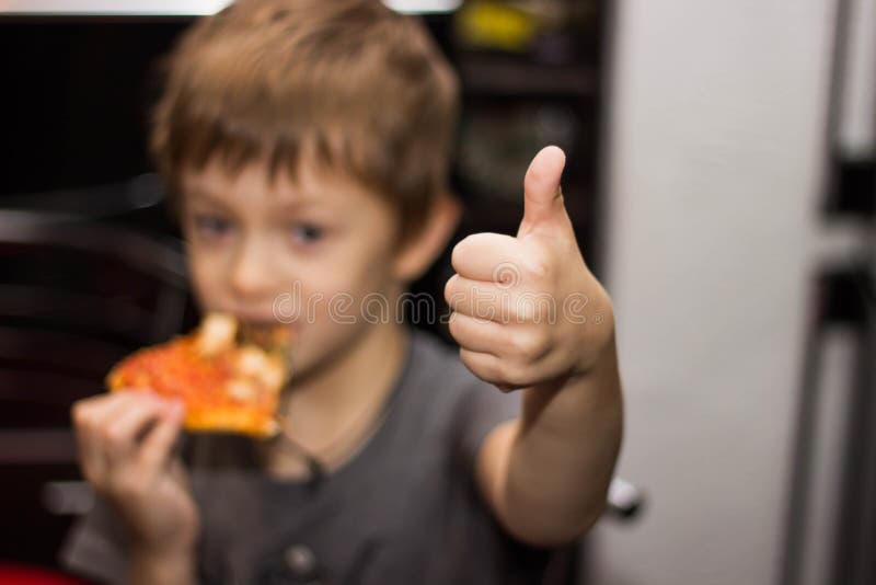 Der Junge isst eine sehr geschmackvolle Pizza mit großem Vergnügen stockfotografie Der Junge isst eine sehr geschmackvolle Pizza mit großem Vergnügen stockfotografie