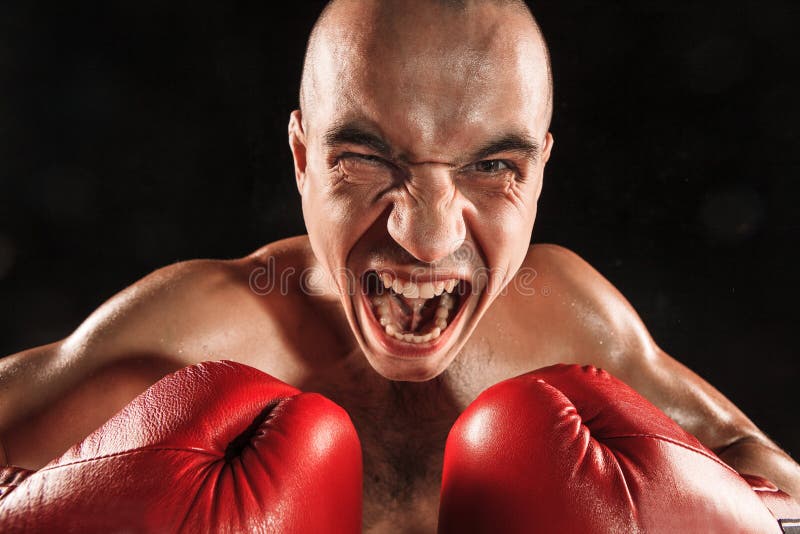 Der junge Mann, der auf Schwarzem mit schreiendem Gesicht kickboxing ist stockfoto Der junge Mann, der auf Schwarzem mit schreiendem Gesicht kickboxing ist stockfoto