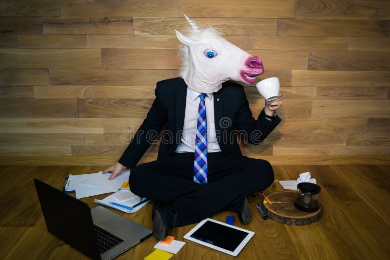 Der junge Mann, der lustige Maske trägt, sitzt auf dem Boden gegen eine Wand und trinkt Kaffee stockfotos Der junge Mann, der lustige Maske trägt, sitzt auf dem Boden gegen eine Wand und trinkt Kaffee stockfotos