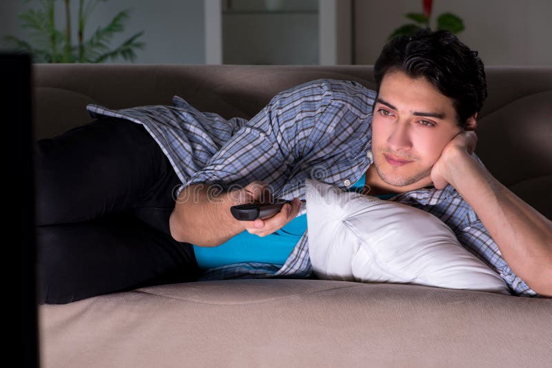 Der junge Mann, der spät nachts fernsieht lizenzfreies stockfoto Der junge Mann, der spät nachts fernsieht lizenzfreies stockfoto