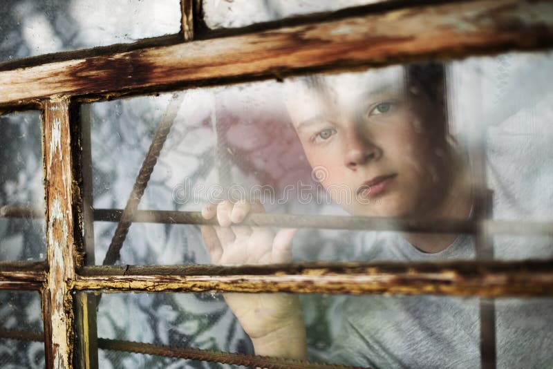 Der Junge Schaut Aus Dem Fenster Heraus Durch Ein Gitter
