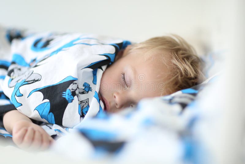 Der Jungenjunge schläft auf einer netten Bettwäsche lizenzfreies stockbild Der Jungenjunge schläft auf einer netten Bettwäsche lizenzfreies stockbild