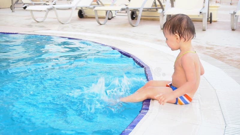 Der kleine Junge sitzt Poolside am Erholungsort stock video footage