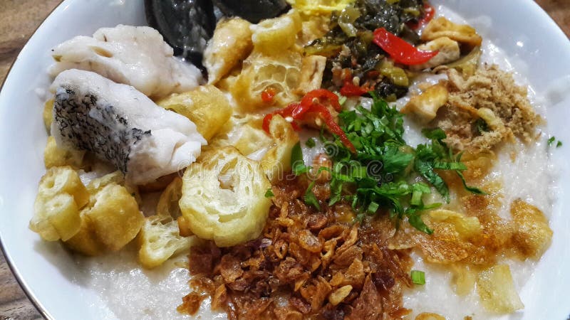 Der köstliche Hühnerbrei, der mit cakwe pitan Eiern überschritten wurde, briet Zwiebelsellerie-Barschfische und Rote Chilis in einer weißen Schale