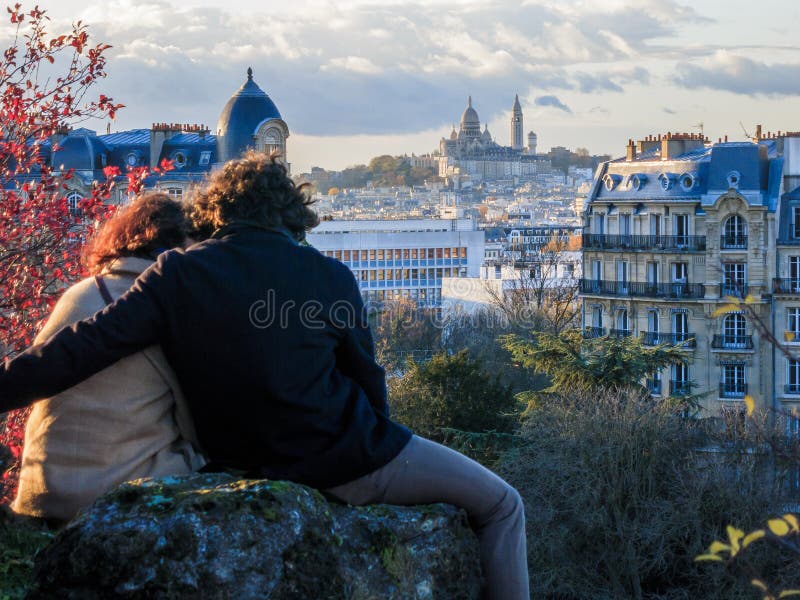 Couple hugging in Parc des Buttes Chaumont, Paris overlooking the city with the Sacre Coeur in the background. Couple hugging in Parc des Buttes Chaumont, Paris overlooking the city with the Sacre Coeur in the background.