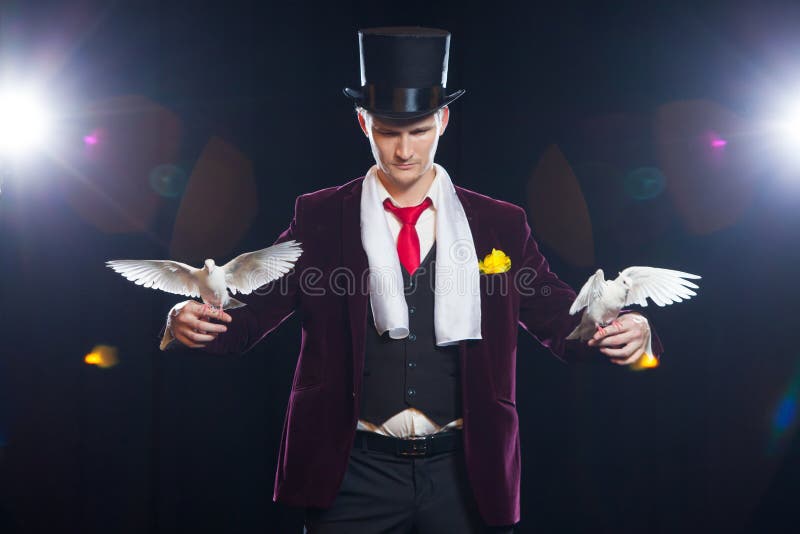 Der Magier mit zwei fliegende weiße Tauben Auf einem schwarzen Hintergrund stockfoto Der Magier mit zwei fliegende weiße Tauben Auf einem schwarzen Hintergrund stockfoto