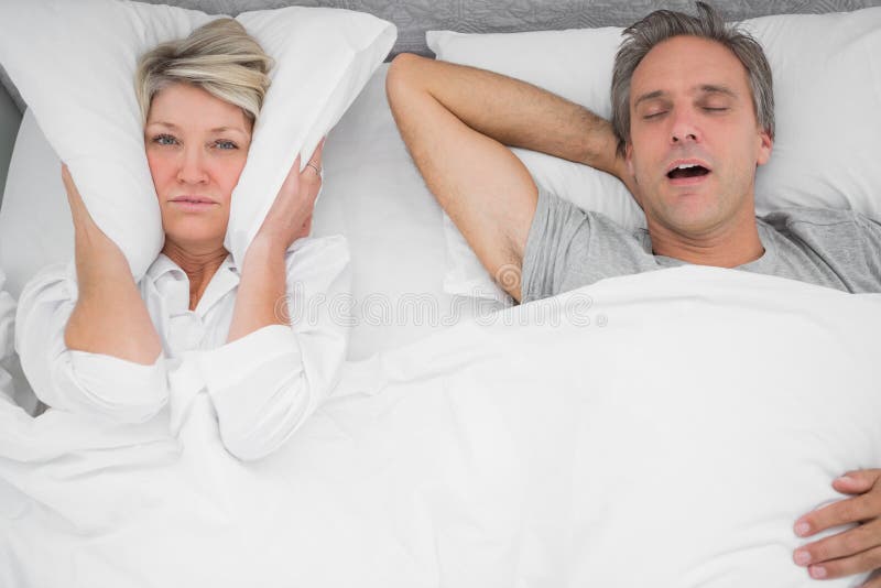 Man snoring loudly as partner blocks her ears at home in bedroom. Man snoring loudly as partner blocks her ears at home in bedroom