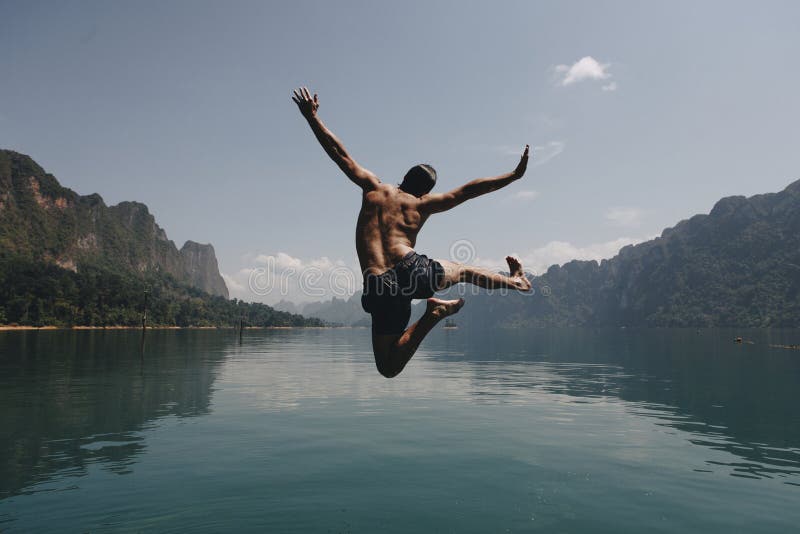 Der Mann springend mit Freude durch einen See