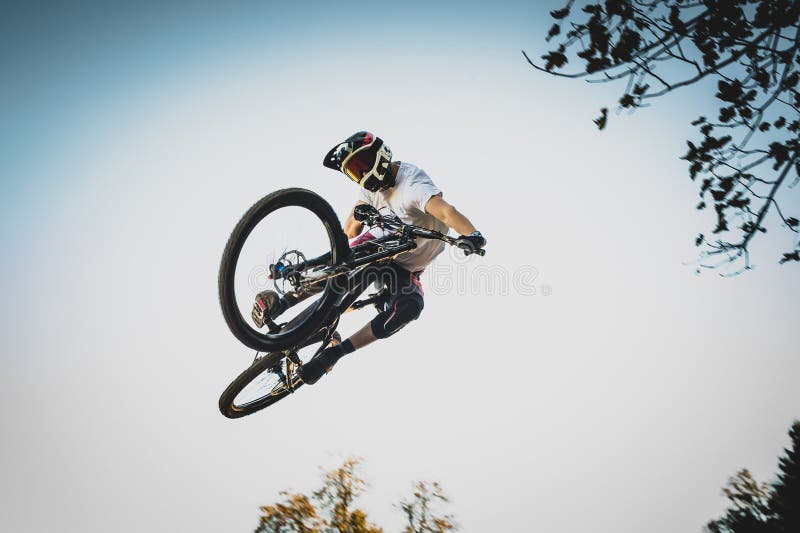 Frontal shot of a mountain biker jumping over a dirt jump in a bike park performing a tail whip. Frontal shot of a mountain biker jumping over a dirt jump in a bike park performing a tail whip