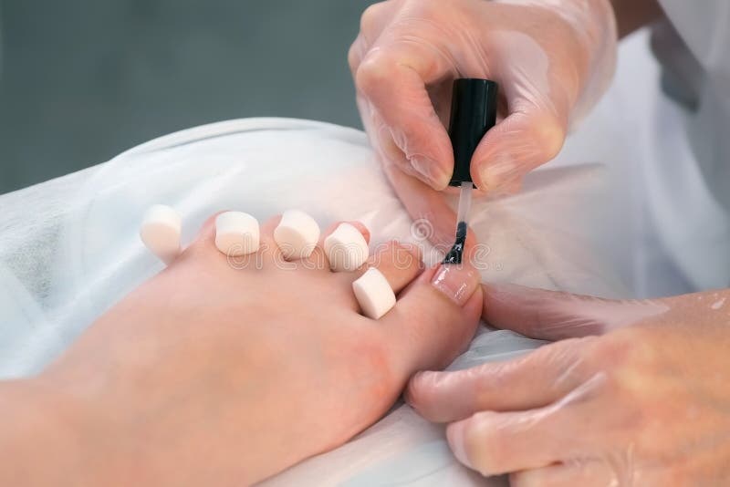 Pedicurist master is applying transparent base coal for shellac on woman& x27;s nails on toes, closeup hands. Preparing nails for shellac in beauty salon. Hygiene and care for feet. Pedicurist master is applying transparent base coal for shellac on woman& x27;s nails on toes, closeup hands. Preparing nails for shellac in beauty salon. Hygiene and care for feet.