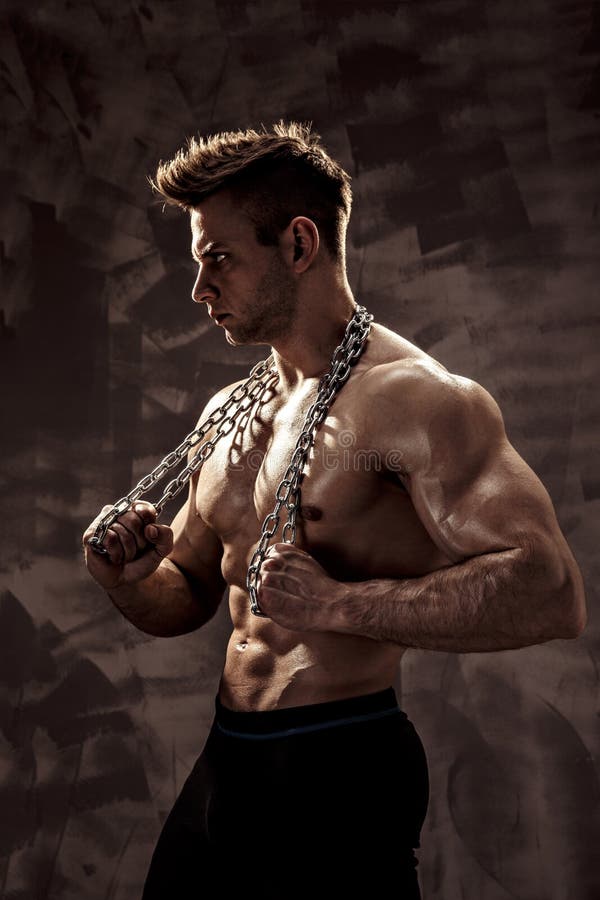 Der perfekte männliche Körper - ehrfürchtige Bodybuilderaufstellung Halten Sie eine Kette mit Tätowierung lizenzfreies stockfoto Der perfekte männliche Körper - ehrfürchtige Bodybuilderaufstellung Halten Sie eine Kette mit Tätowierung lizenzfreies stockfoto