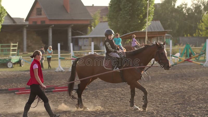 Der Trainer unterrichtet das Kind, zu Pferd zu sitzen