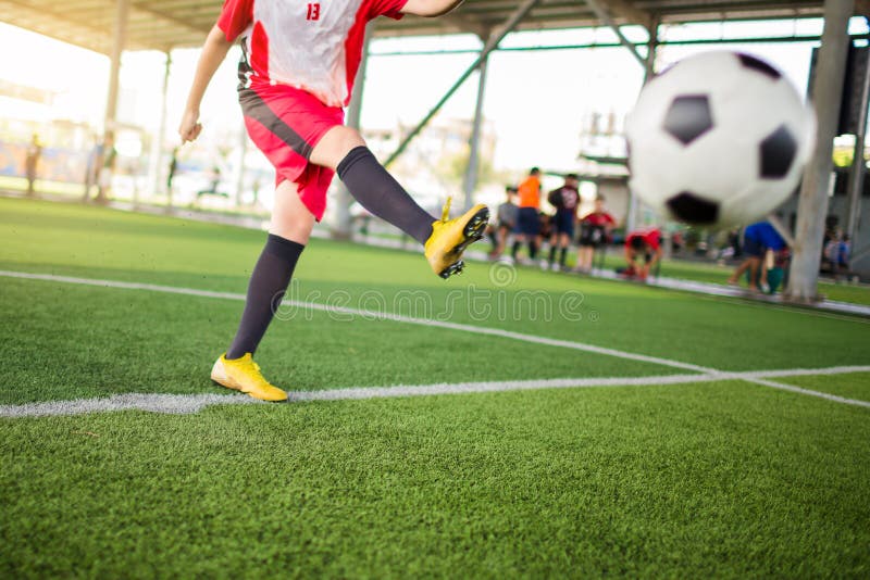 Der unscharfe Ball nach der Geschwindigkeit des Fußballspielers läuft auf dem grünen Kunstrasen, um es auf das Ziel zu schießen Fußballspielertraining Asiatischer Jungenspieler an der Fußballakademie