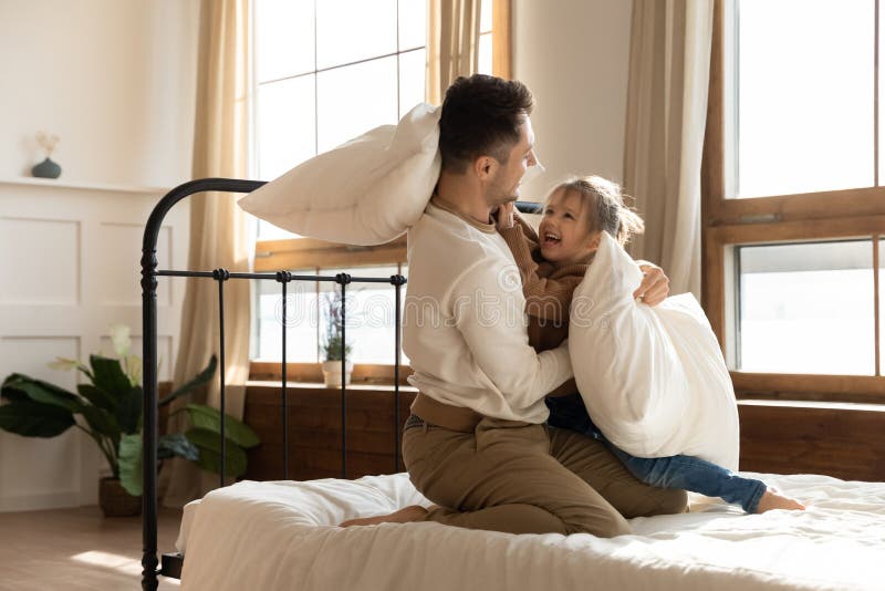 Der Vater und Tochter sitzen im Bett kämpfen mit Beutel lizenzfreie stockfotografie