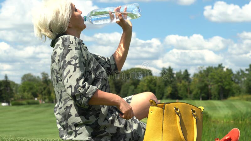 Der von mittlerem Alter Trinkwasser Frau von einer Flasche