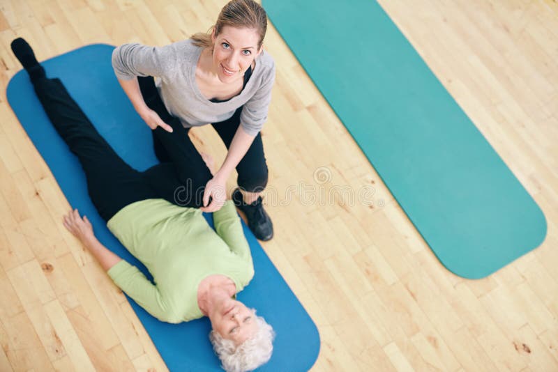 Der weibliche Trainer, welche älterer Frau hilft, tun Beinausdehnungen an der Rehabilitation stockfoto Der weibliche Trainer, welche älterer Frau hilft, tun Beinausdehnungen an der Rehabilitation stockfoto