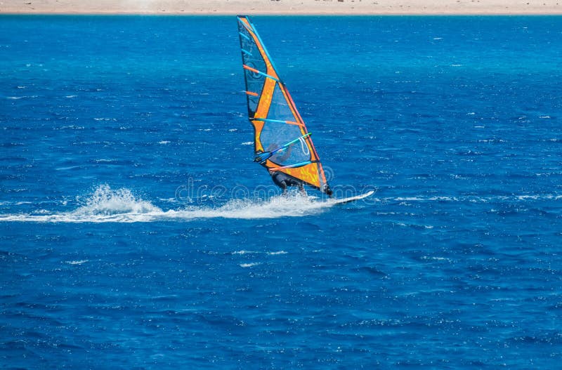 Der Windsurfer auf dem Brett unter Segel zieht mit einer Geschwindigkeit entlang der Meeresoberfläche um stockfoto Der Windsurfer auf dem Brett unter Segel zieht mit einer Geschwindigkeit entlang der Meeresoberfläche um stockfoto