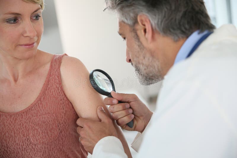 Dermatolog patrzeje kobiety moke obraz stock Dermatolog patrzeje kobiety moke obraz stock
