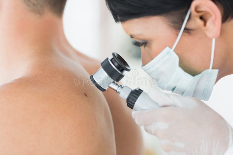 Dermatologist examining mole on patient