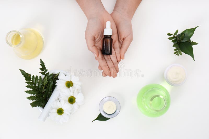 Dermatologista fêmea com a garrafa do produto dos cuidados com a pele e os ingredientes no fundo branco