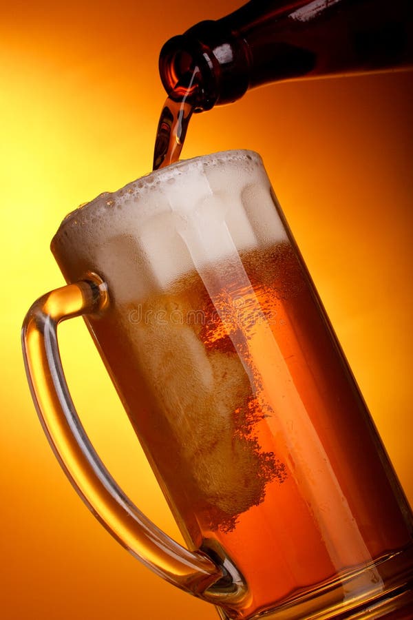 Dark beer pouring into mug on a yellow background. Dark beer pouring into mug on a yellow background.