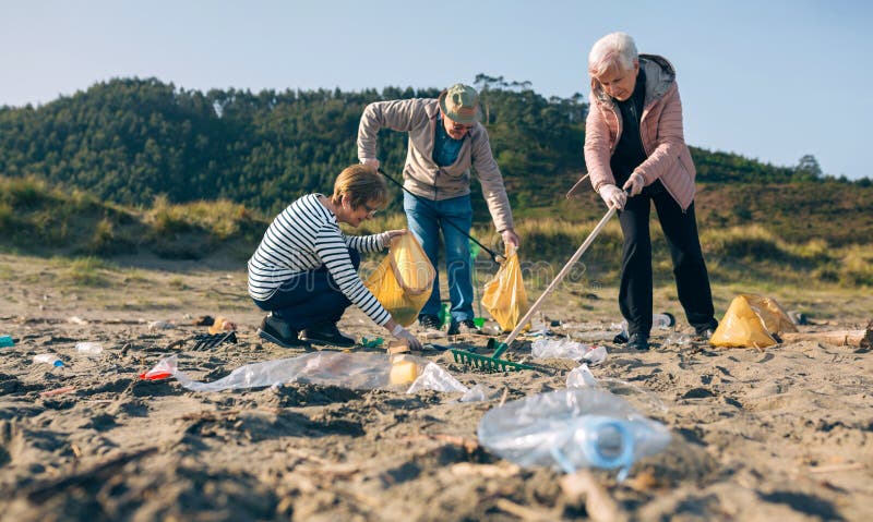 Des bénévoles supérieurs nettoient la plage photos stock