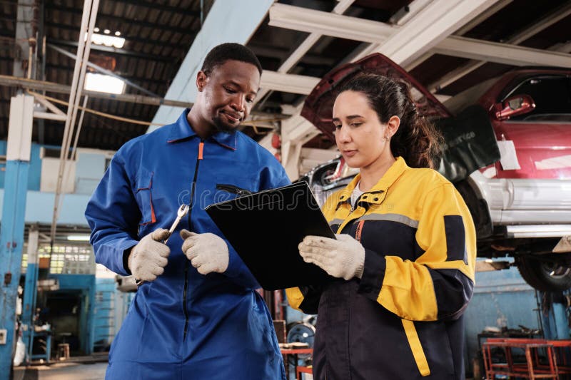Des collègues mécaniciens discutant des travaux de service dans le garage. photos stock
