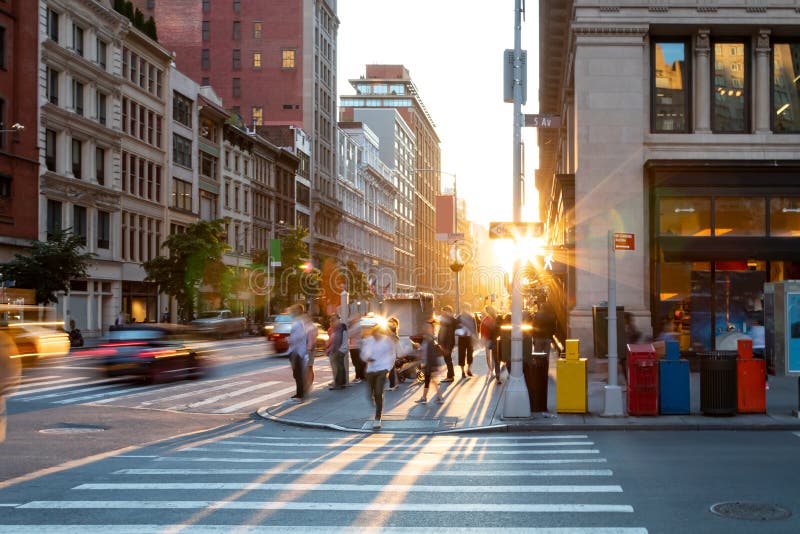 Man walking through the crosswalk at the busy intersection of 5th Avenue and 23rd Street in New York City with bright light of sunset in the background. Man walking through the crosswalk at the busy intersection of 5th Avenue and 23rd Street in New York City with bright light of sunset in the background