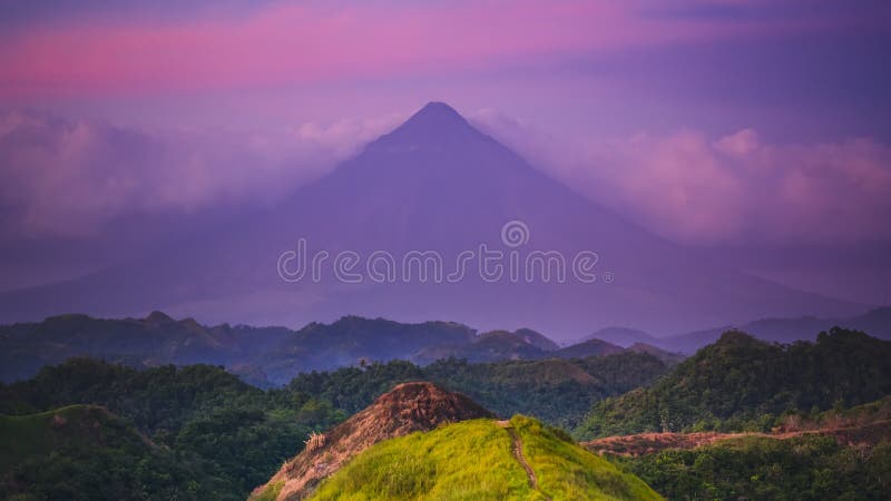 Des nuages violets denses entourent la silhouette du volcan Mayon banque de vidéos
