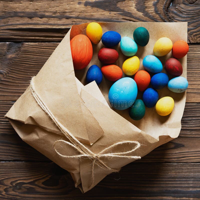 Des oeufs de p?ques sont emball?s dans un sac de papier comme cadeau sur un fond en bois photos libres de droits Des oeufs de p?ques sont emball?s dans un sac de papier comme cadeau sur un fond en bois photos libres de droits