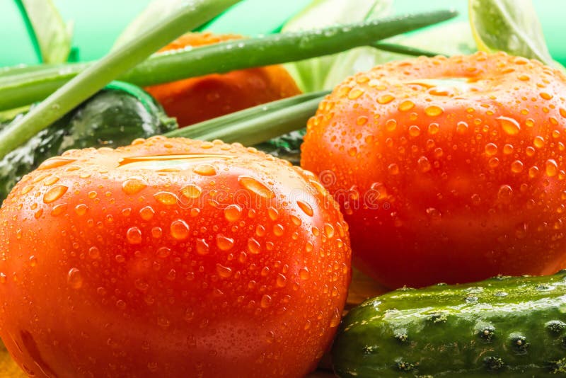 Des tomates rouges mûres, concombres verts, des plumes d'oignon vert sont couvertes de grandes gouttes de l'eau image stock Des tomates rouges mûres, concombres verts, des plumes d'oignon vert sont couvertes de grandes gouttes de l'eau image stock