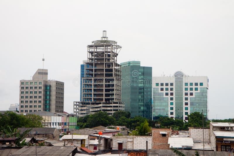 Office building construction foregrounded by neighboring slums in a city of the third world country. Office building construction foregrounded by neighboring slums in a city of the third world country.