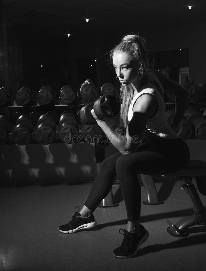 Desaturated foto av den sexiga sportkvinnan med hanteln fotografering för bildbyråer Desaturated foto av den sexiga sportkvinnan med hanteln fotografering för bildbyråer
