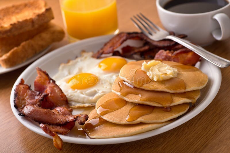 Desayune con tocino, huevos, las crepes, y la tostada