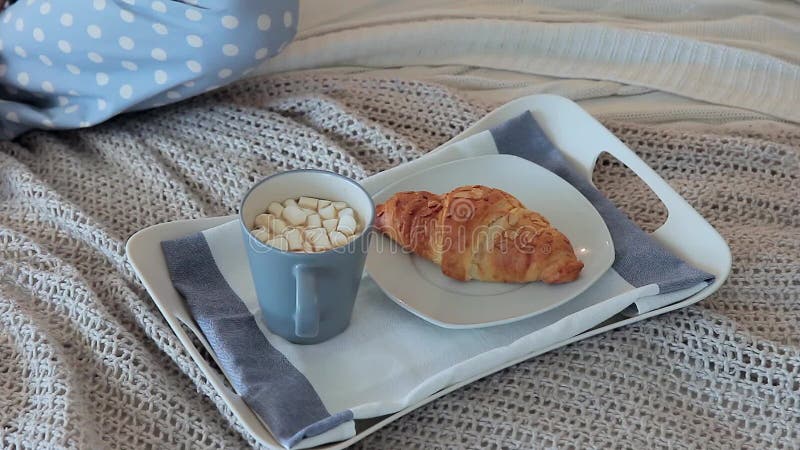 Desayune en cama con café y un cruasán para una mujer atractiva joven