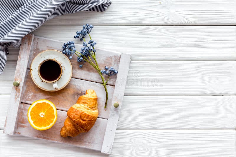 Desayuno en cama con el cruasán, café en taza con la naranja en la bandeja en la opinión de top de madera blanca del fondo imagen de archivo libre de regalías Desayuno en cama con el cruasán, café en taza con la naranja en la bandeja en la opinión de top de madera blanca del fondo imagen de archivo libre de regalías
