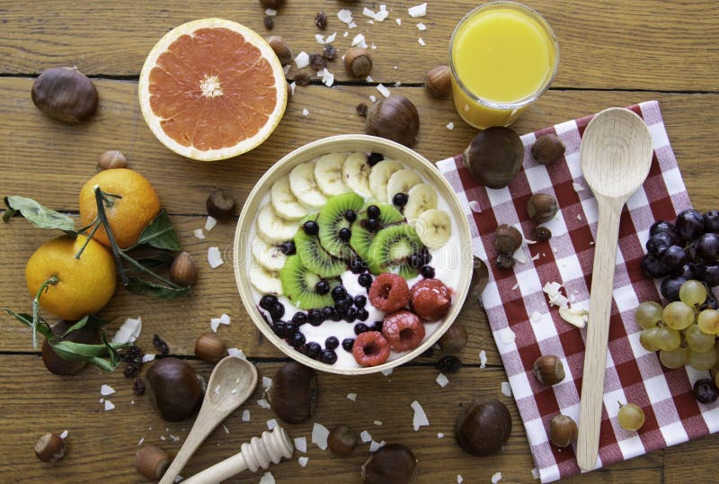Desayuno natural fresco sano con el yogur, las frutas, el jugo y las nueces en la tabla de madera Visión superior Concepto sobre imagen de archivo Desayuno natural fresco sano con el yogur, las frutas, el jugo y las nueces en la tabla de madera Visión superior Concepto sobre imagen de archivo