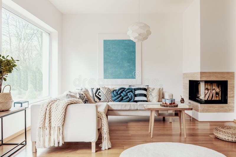 Descanso do nó do azul de turquesa em um sofá de canto bege e em um cartaz abstrato em uma parede branca em um interior moderno d