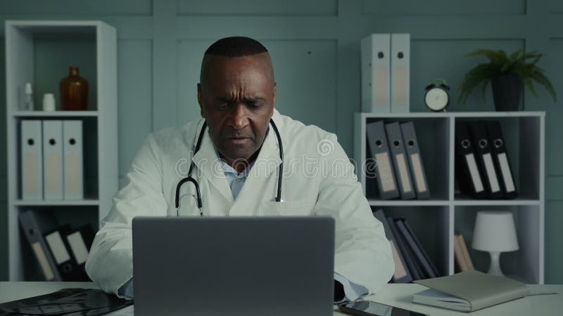 Desconcertado doctor adulto de edad hombre afroamericano pensar usar laptop participar conferencia webcam ayudar a distantes almacen de metraje de vídeo