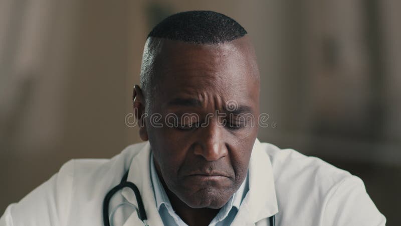 Desconcertado pensante médico profesional masculino maduro médico adulto afroamericano en la idea de planificación de abrigos médi almacen de video