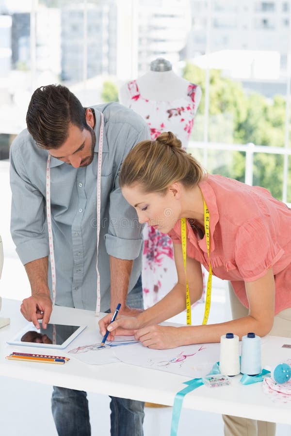 Desenhadores de moda no trabalho no estúdio brilhante imagens de stock Desenhadores de moda no trabalho no estúdio brilhante imagens de stock