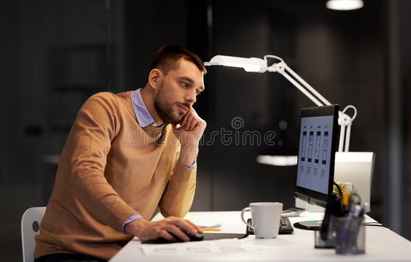 Desenhista da Web com funcionamento do computador no escritório da noite imagem de stock Desenhista da Web com funcionamento do computador no escritório da noite imagem de stock