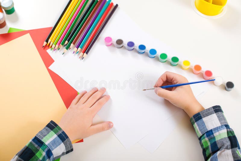 Desenho do ` s da criança Fundo da arte com lápis coloridos, pinturas e papel vazio Mãos da criança com escova em um papel ` S da imagem de stock Desenho do ` s da criança Fundo da arte com lápis coloridos, pinturas e papel vazio Mãos da criança com escova em um papel ` S da imagem de stock