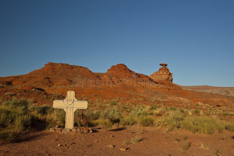 Memorial cross in the Utah desert with the Mexican Hat formation in the background. Memorial cross in the Utah desert with the Mexican Hat formation in the background.